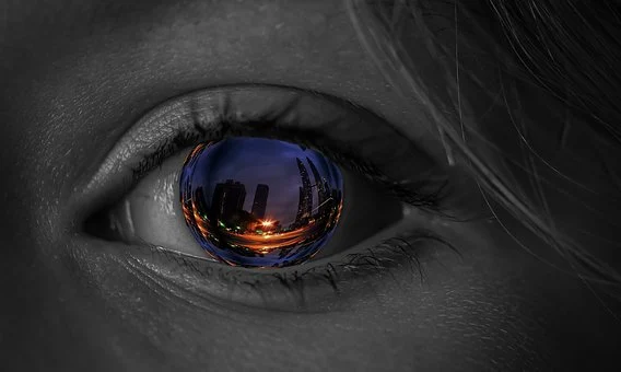 Photo d'un oeil où reflète une ville, comme un représentation de ce que peut imaginer la personne